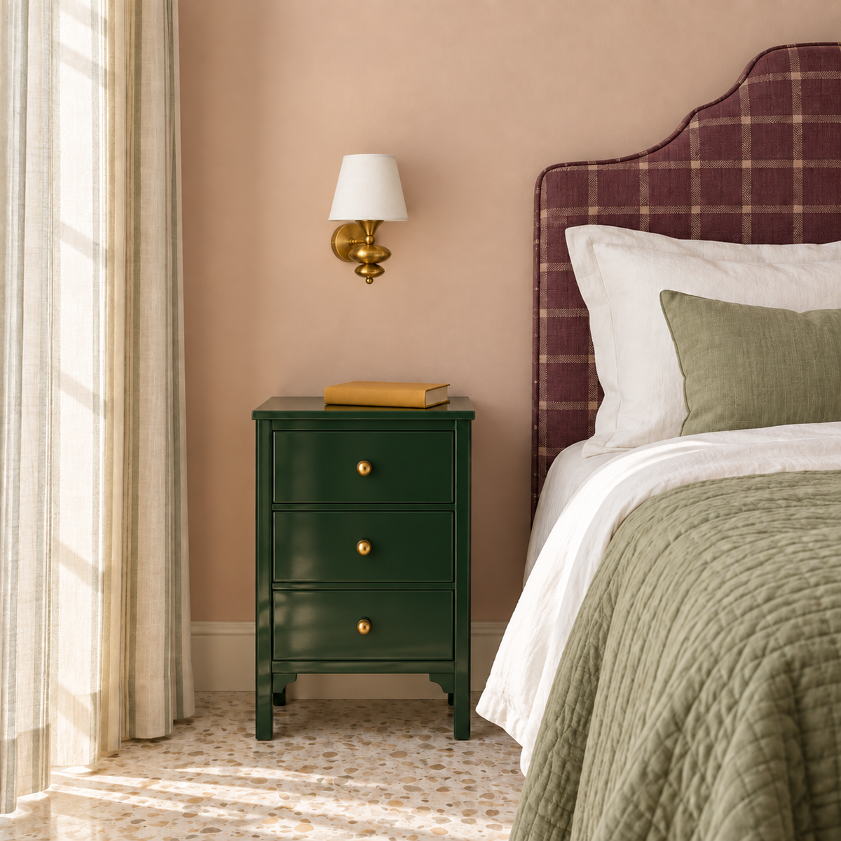 White shade sculpted-finial wall light beside an upholstered bed in daylight, switched off