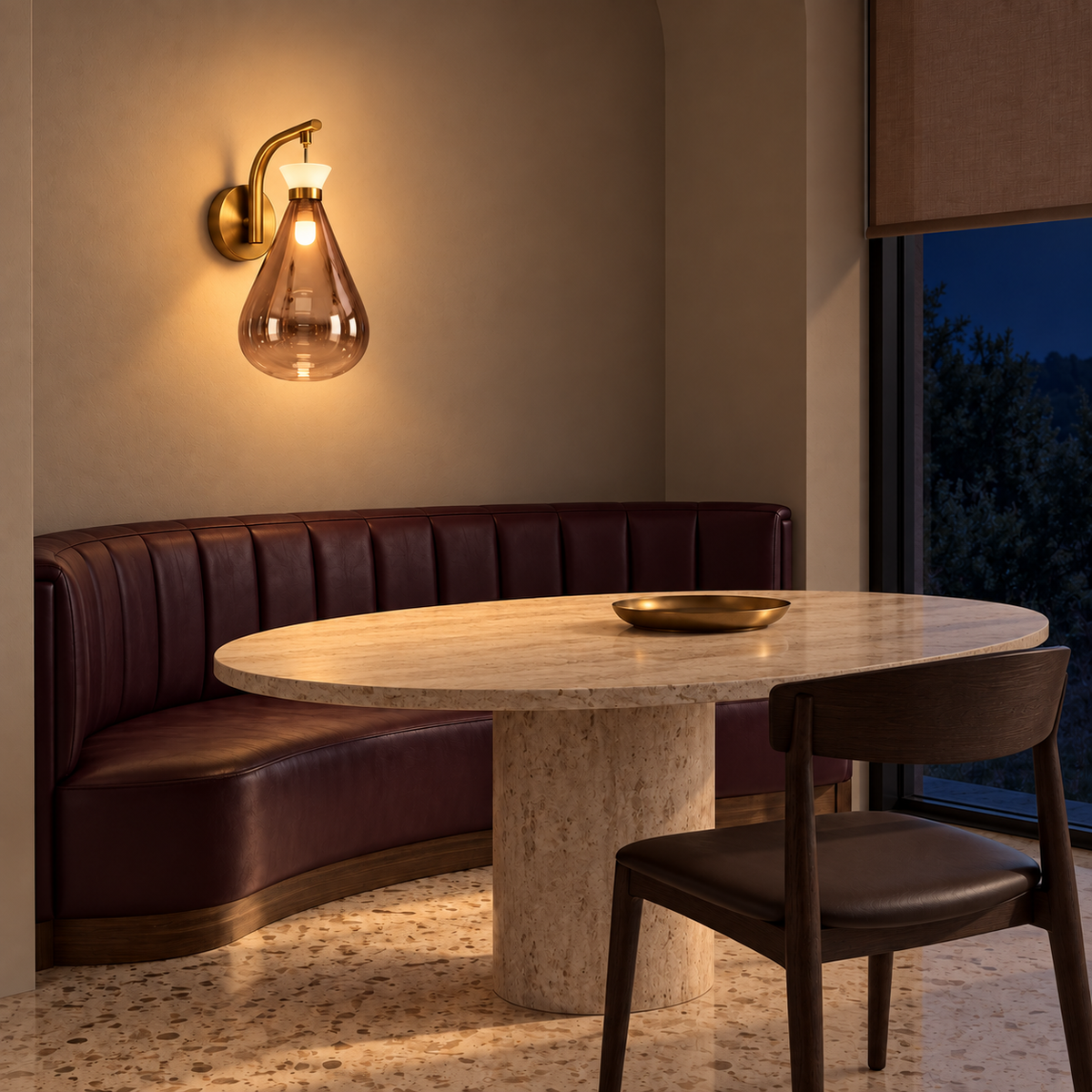 Tinted teardrop glass wall light illuminated above a dining banquette at night