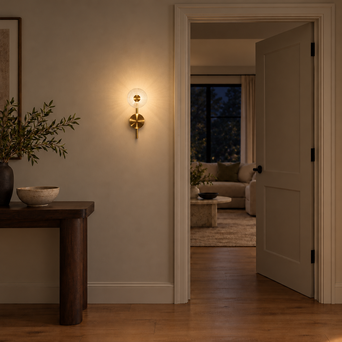 Textured clear glass disc wall light illuminated beside an open doorway and wooden console at night.