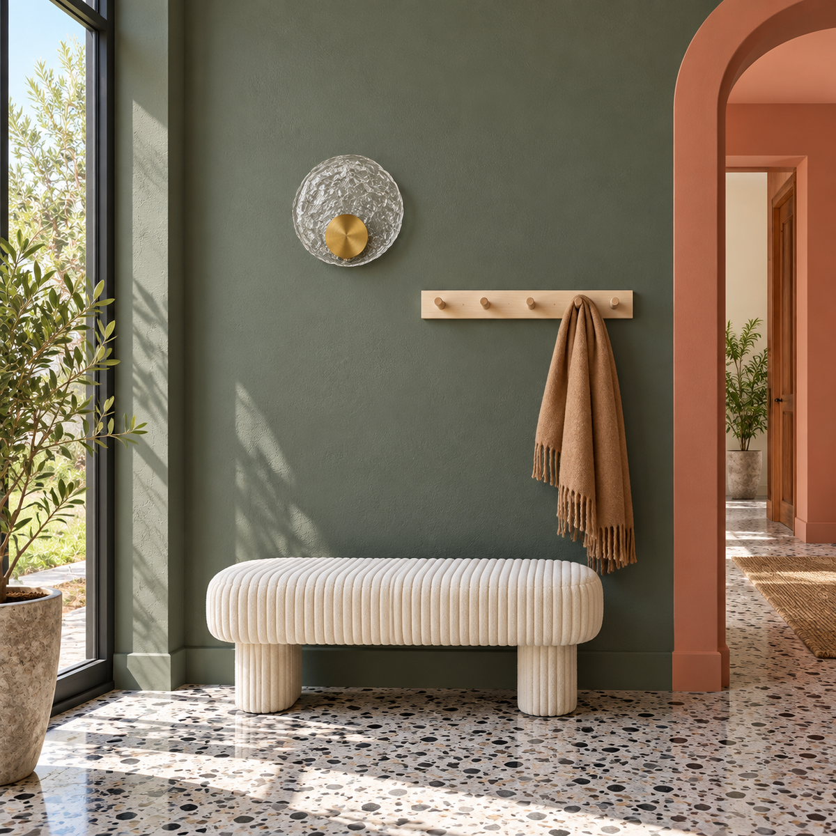 Textured glass disc wall light above a pale upholstered bench in daylight, switched off