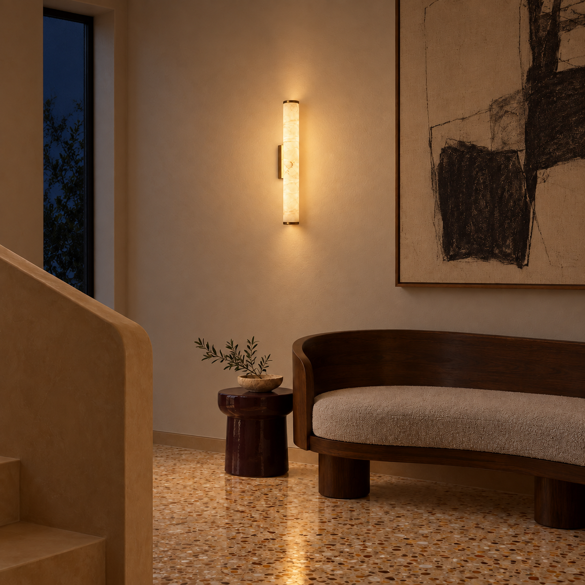 Stone-effect column wall light illuminated beside abstract artwork and a curved bench at night