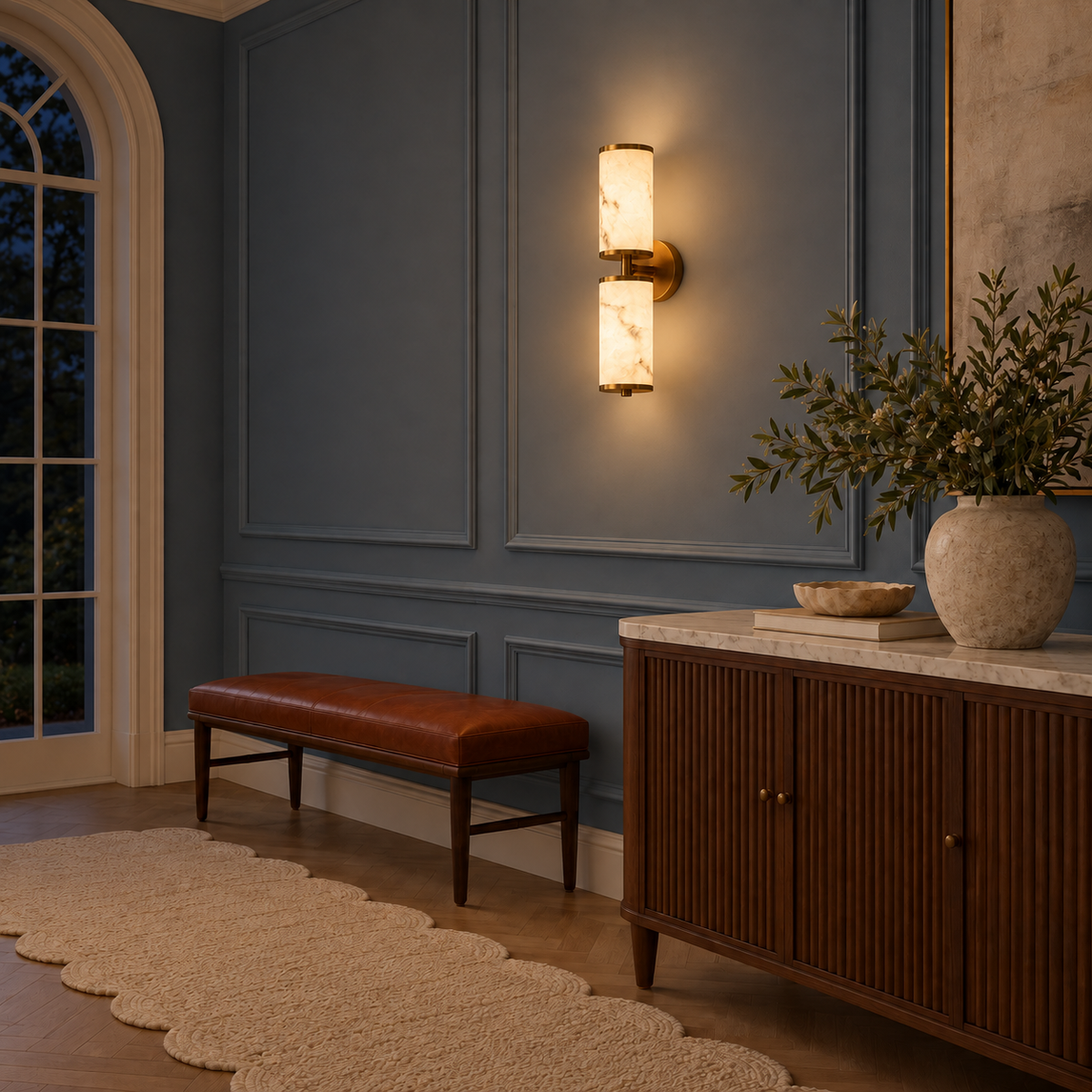 Twin stone-effect cylinder wall light illuminated above a bench beside a sideboard at night