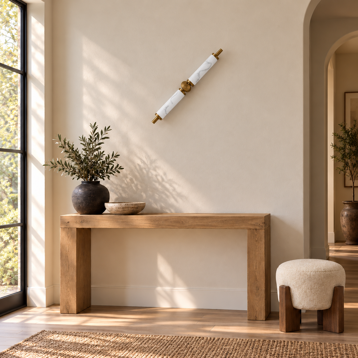 Twin cylinder marble-effect resin wall light above an oak console in a bright entryway