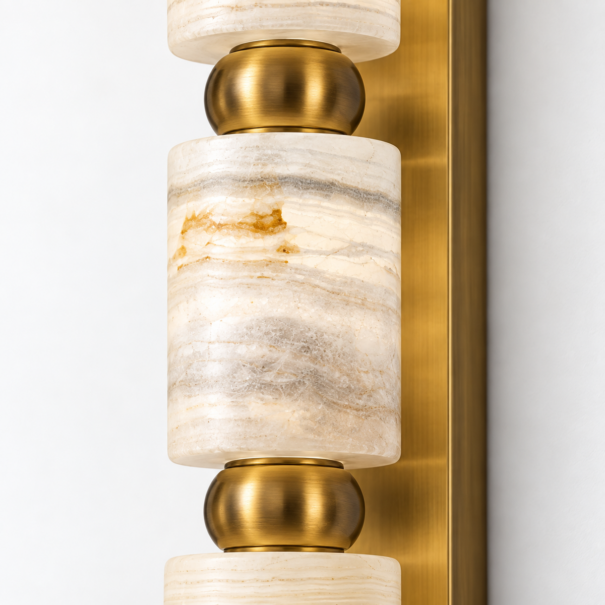 Close-up detail of the marble and gold three-cylinder wall light