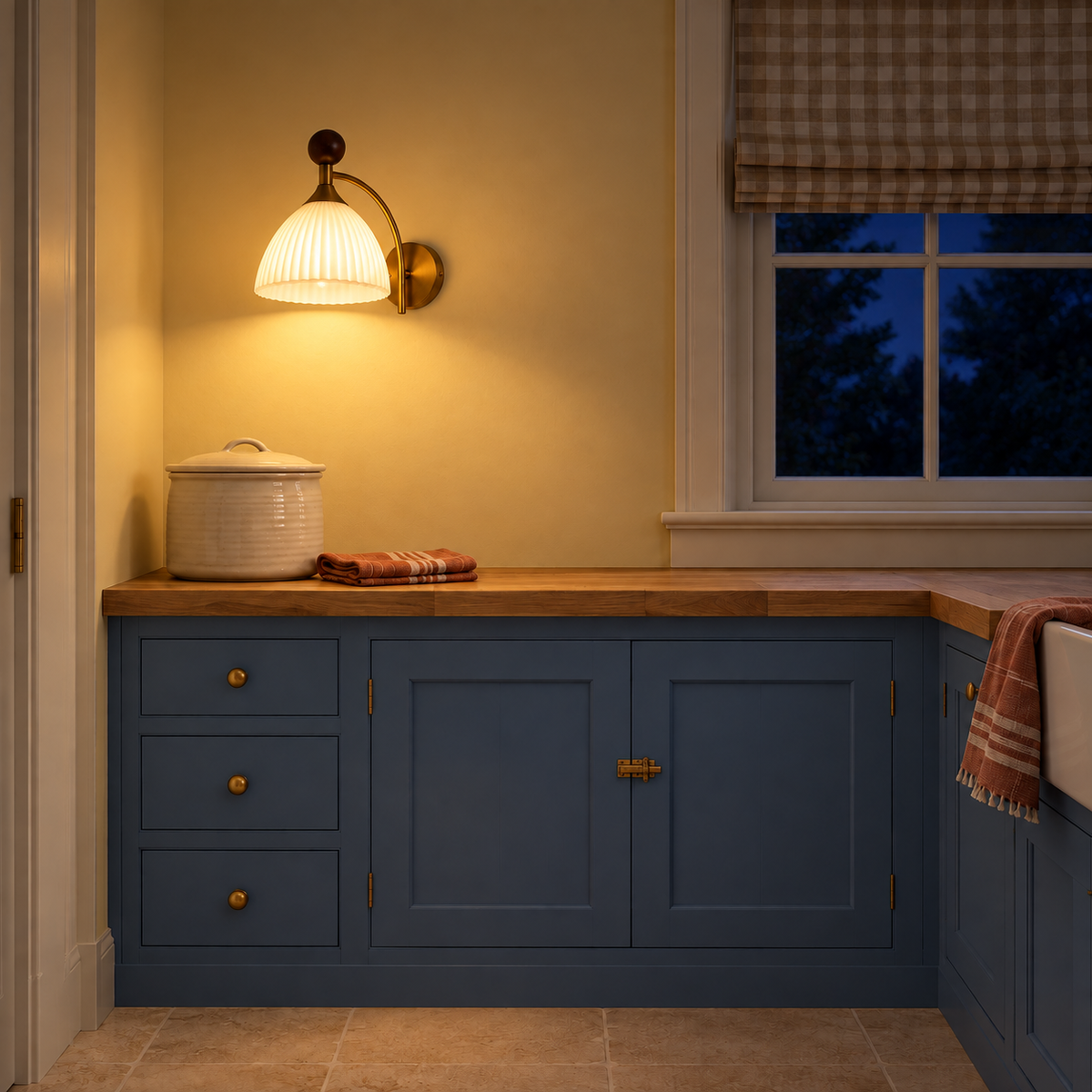 Ribbed white glass wood-finial wall light illuminated above blue kitchen cabinets at night