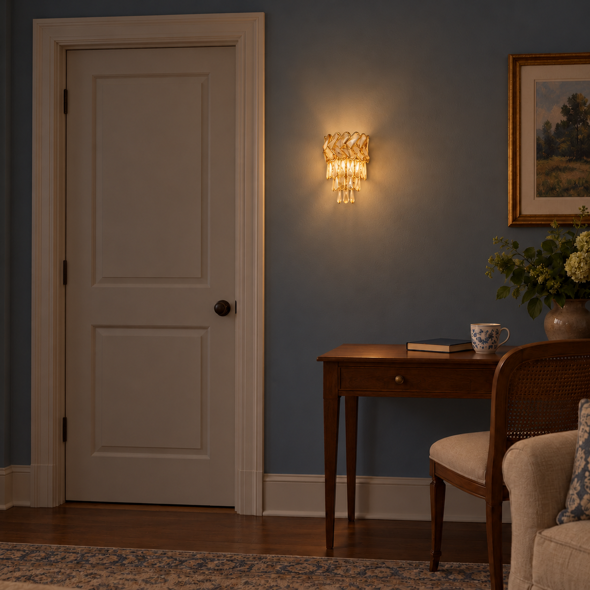 Gold chevron cascade wall light illuminated on a blue wall beside a white door and writing desk at night.