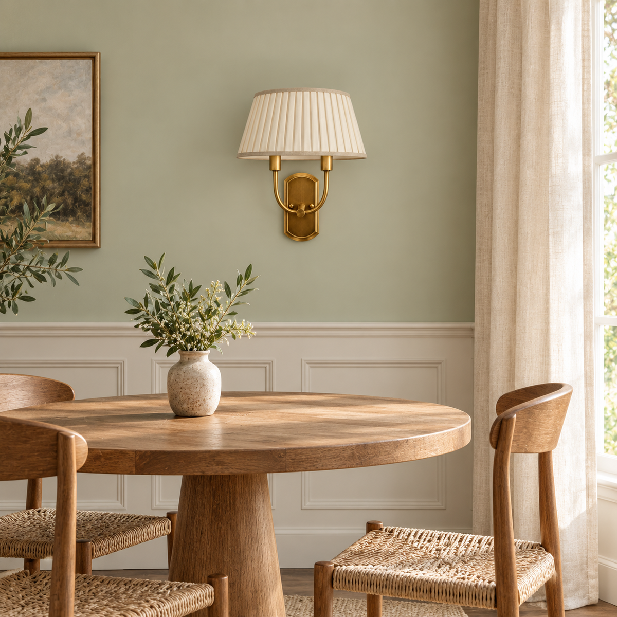 Twin Arm Pleated Shade Wall Light above a round dining table beside framed artwork in daylight, switched off