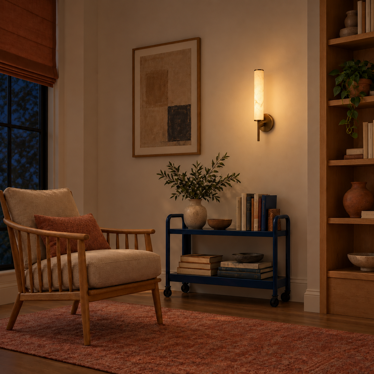 Stone-effect cylinder wall light illuminated beside artwork and a reading chair at night