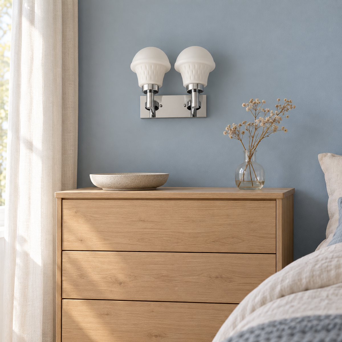 Twin Ribbed Bell Chrome Wall Light above a wood chest beside an upholstered bed in daylight, switched off