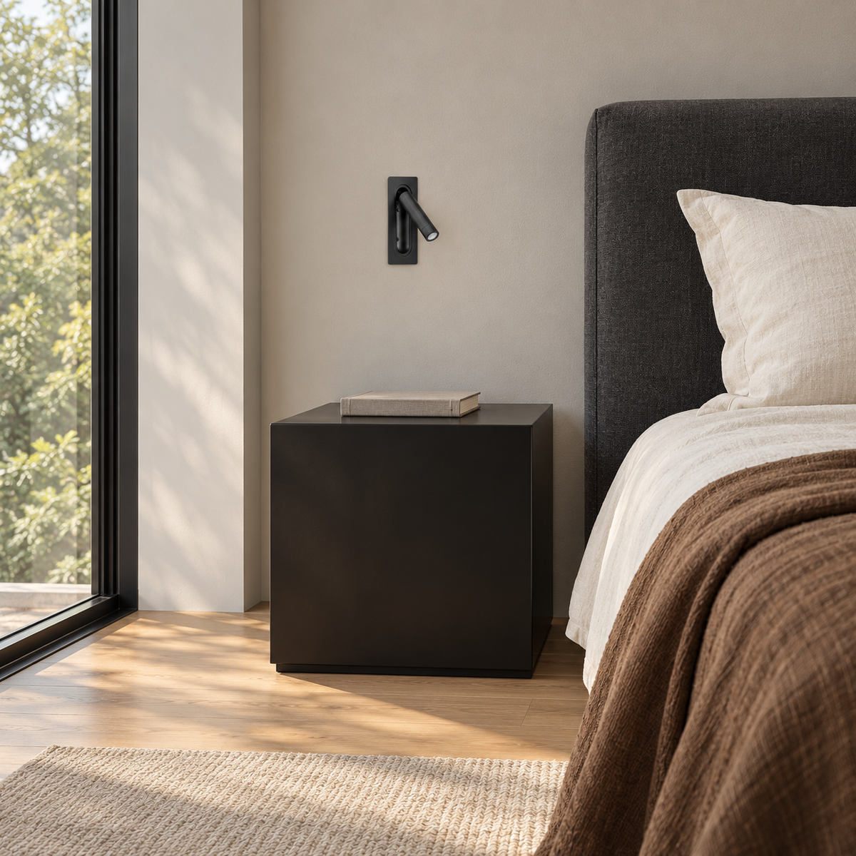 Black Recessed Cylindrical Reading Wall Light above a bedside cabinet in daylight, switched off